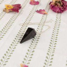 Load image into Gallery viewer, Nuummite Faceted Pendulum on a style background - Down To Earth
