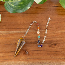 Load image into Gallery viewer, Tiger's Eye Faceted Pendulum with 7 Chakra top down on a style background - Down To Earth
