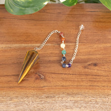 Load image into Gallery viewer, Tiger's Eye Faceted Pendulum with 7 Chakra angled on a style background - Down To Earth
