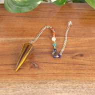 Tiger's Eye Faceted Pendulum with 7 Chakra angled on a style background - Down To Earth