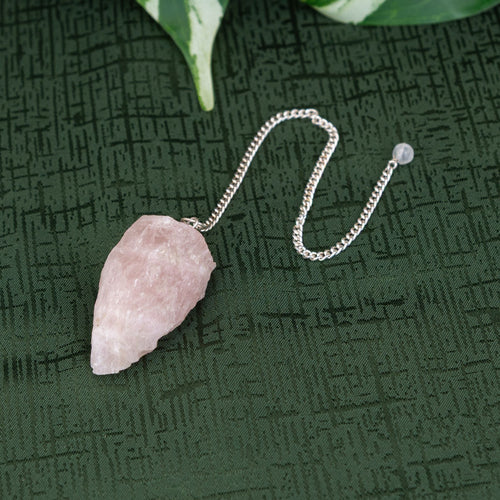 Raw Rose Quartz Pendulum on a green background - Down to Earth 