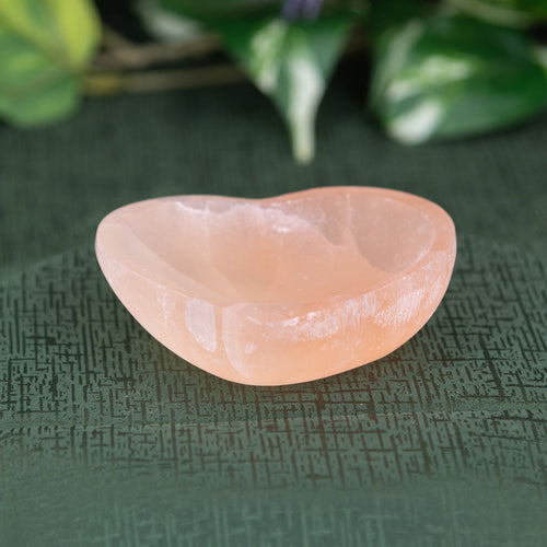 Red Selenite Heart Bowl on a green background - Down to Earth