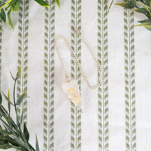 Load image into Gallery viewer, Clear Quartz Reiki Faceted Pendulum on a white and green cloth top down photo - Down to Earth
