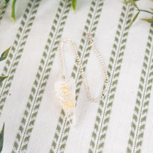 Load image into Gallery viewer, Clear Quartz Reiki Faceted Pendulum on a white and green cloth close-up photo - Down to Earth
