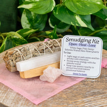 Load image into Gallery viewer, "Rose Quartz Smudging Kit that includes raw Rose Quartz, White Sage, Palo Santo, a 4'' Selenite Wand, an info card, and a pink organza bag," - Down to Earth.
