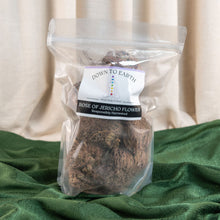Load image into Gallery viewer, "Packaged Rose of Jericho flowers with 'Down to Earth' label on a green fabric background," - Down to Earth.
