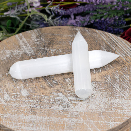 Selenite Point Wands sitting on a tray with flowers in the foreground - Down To Earth