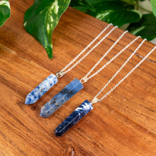 Load image into Gallery viewer, "Three Sodalite Point Pendant necklaces on silver chains displayed on a wooden surface with green leaves in the background," - Down to Earth.
