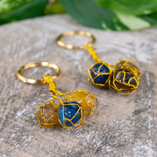 Load image into Gallery viewer, Triple Caged Gemstone Key Chain on a wooden surface - Down to Earth 
