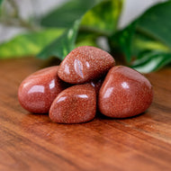 Red Goldstone Tumbled on a wooden surface - Down to Earth 