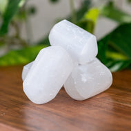 Selenite Tumbled on a wooden surface - Down to Earth 