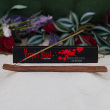 Load image into Gallery viewer, Vampire Blood Incense Stick lit on a holder with box in background with a floral background - Down to Earth 
