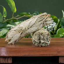 Load image into Gallery viewer, White Sage Smudge Stick 2x5 with plants displayed on a styled background - Down to Earth
