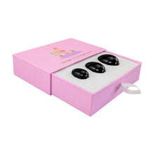 Load image into Gallery viewer, &quot;Three pieces of black obsidian yoni eggs in an open light pink box against a white background,&quot; - Down to Earth.
