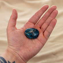 Load image into Gallery viewer, Photo of a blue apatite palm stone being held in a hand. Blue apatite is a deep blue stone with some brown streaks. - Down to Earth.
