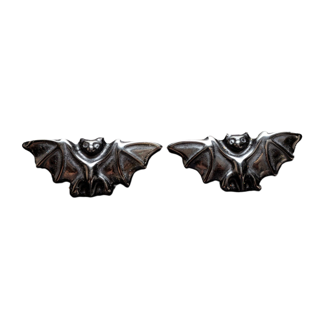 Top down view of two black obsidian crystal bats with wings spread open. These stone statues are approximately two inches long. - Down to Earth.