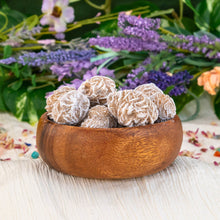 Load image into Gallery viewer, &quot;Wooden bowl overflowing with raw desert rose, a form of selenite, with a floral background,&quot; - Down to Earth.
