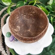 Load image into Gallery viewer, "Coconut bowl on a white stand with green leaves in the background," - Down to Earth.
