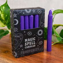 Load image into Gallery viewer, "Box of purple 'Magic Spell Candles' with one candle standing on a wooden surface," - Down to Earth.
