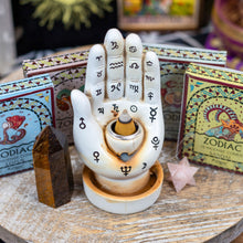 Load image into Gallery viewer, &quot;A palmistry backflow incense burner with smoke billowing out of its base, surrounded by zodiac incense cones and crystals,&quot; - Down to Earth.
