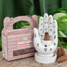 Load image into Gallery viewer, &quot;Single package of Positive Vibes Backflow Dhoop Cones next to a Palmistry Incense Burner on a wooden plank with green foliage in the background,&quot; - Down to Earth.
