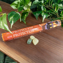 Load image into Gallery viewer, "HEM Protection Incense Sticks on a wooden platform with green crystals in front and foliage in the background," - Down to Earth.
