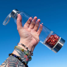 Load image into Gallery viewer, &quot;A clear water bottle with Red Jasper crystal chips in the bottom chamber held up with a clear blue sky in the background,&quot; - Down to Earth.
