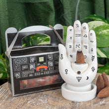 Load image into Gallery viewer, &quot;Single package of Satya Super Hit Backflow Incense Cones next to a Palmistry Incense Burner on a wooden plank with green foliage in the background,&quot; - Down to Earth.
