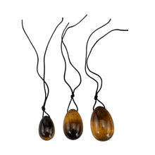 Load image into Gallery viewer, &quot;Three pieces of tiger&#39;s eye yoni eggs with black string tied to the top,&quot; - Down to Earth.
