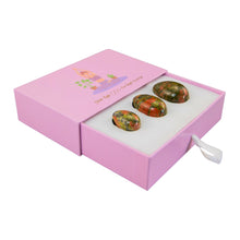 Load image into Gallery viewer, &quot;Left-side view of an open light pink box with three unakite yoni eggs inside against a white background,&quot; - Down to Earth.
