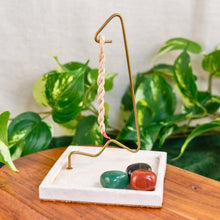 Load image into Gallery viewer, "Decorative rope incense burner with three crystals at the base with green foliage in the background," - Down to Earth.
