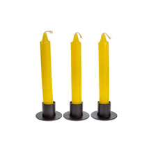Load image into Gallery viewer, Front view of three yellow ritual candles standing upright in black metal candle holders. - Down to Earth.
